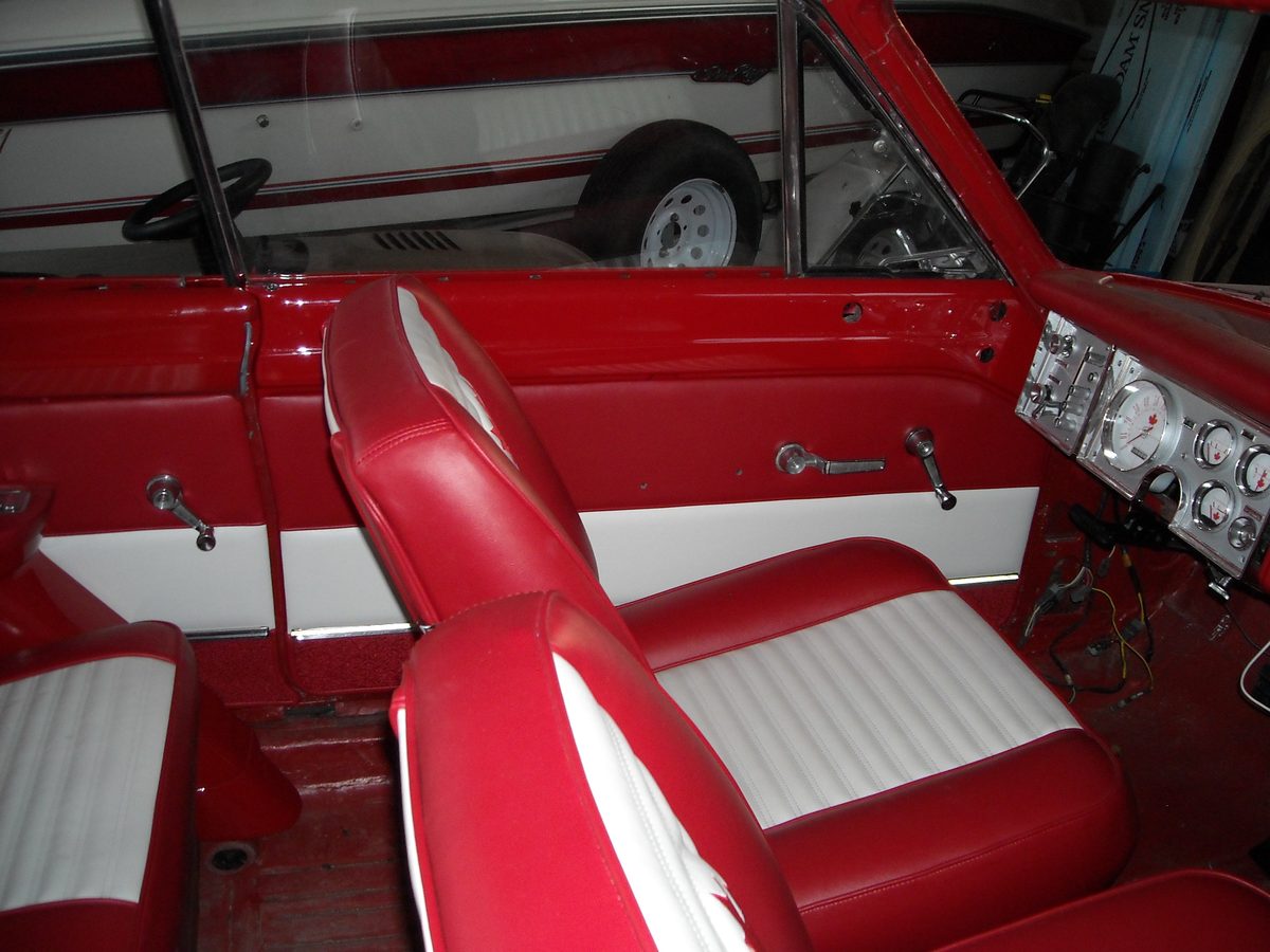 The interior of a classic car in red and white vinyl, with matching seats and door panels.