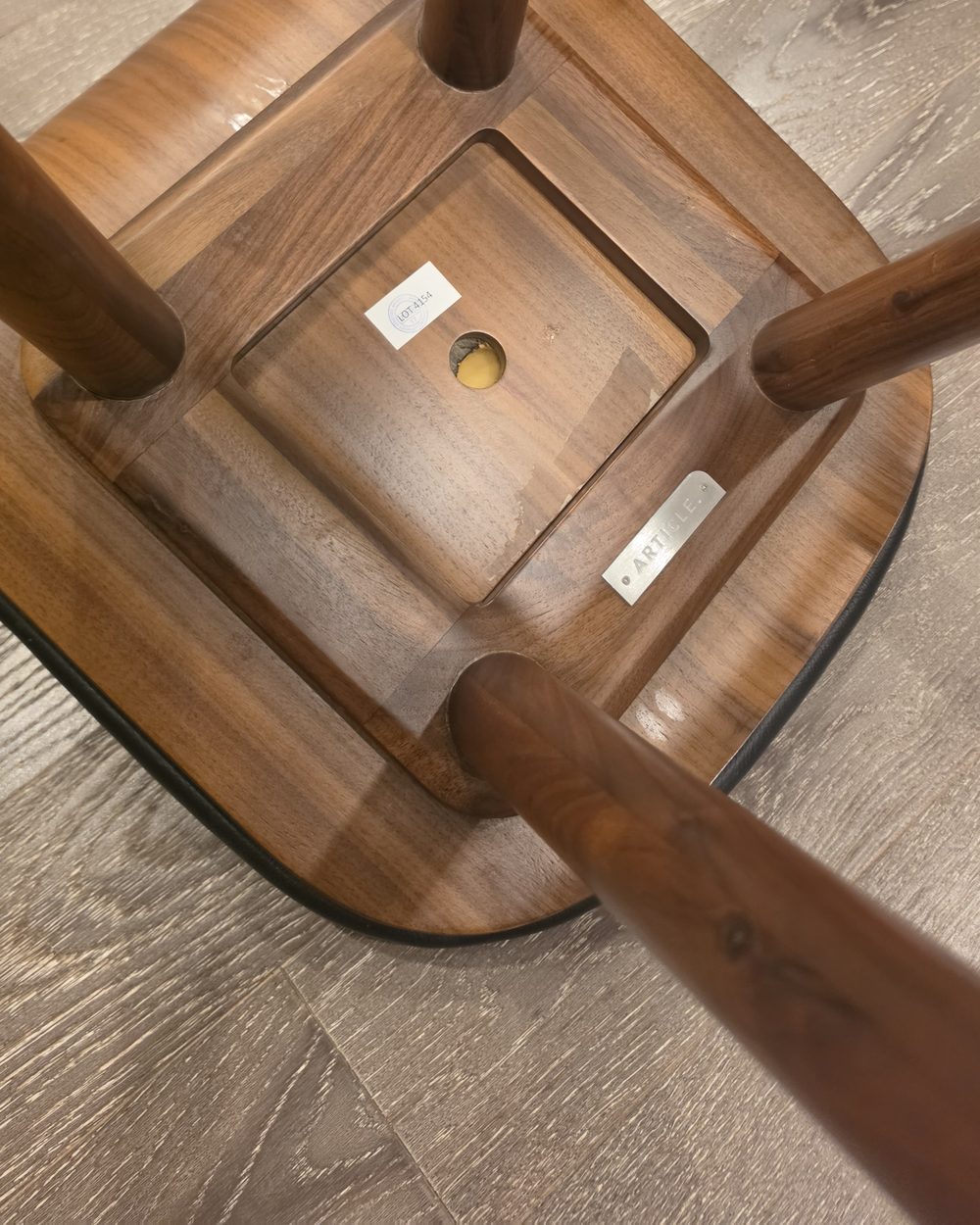 The underside of a walnut counter stool, all smooth wood with no screws or bolts anywhere in sight.